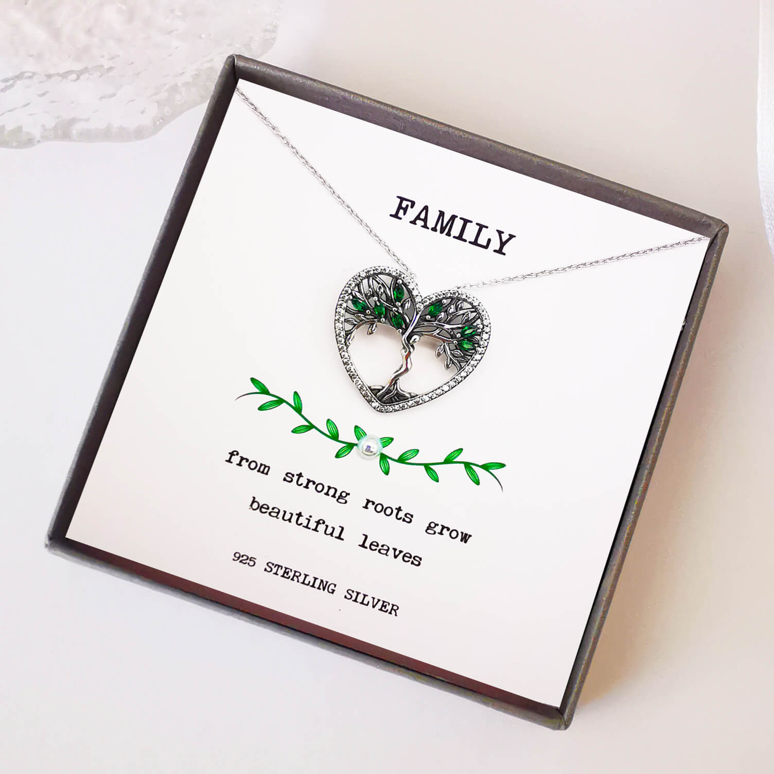 High quality detailed sterling silver tree of life pendant necklace with green zirconia. Boxed with handmade and hand embellished insert with the quote "from strong roots grow beautiful leaves".  Unique family gift keepsake for mum, sister, aunt, grandmother.